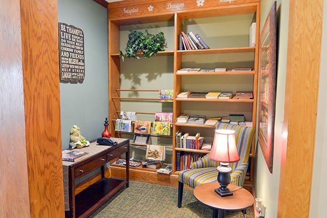 A cozy reading nook with wooden shelves filled with books and a comfortable armchair.