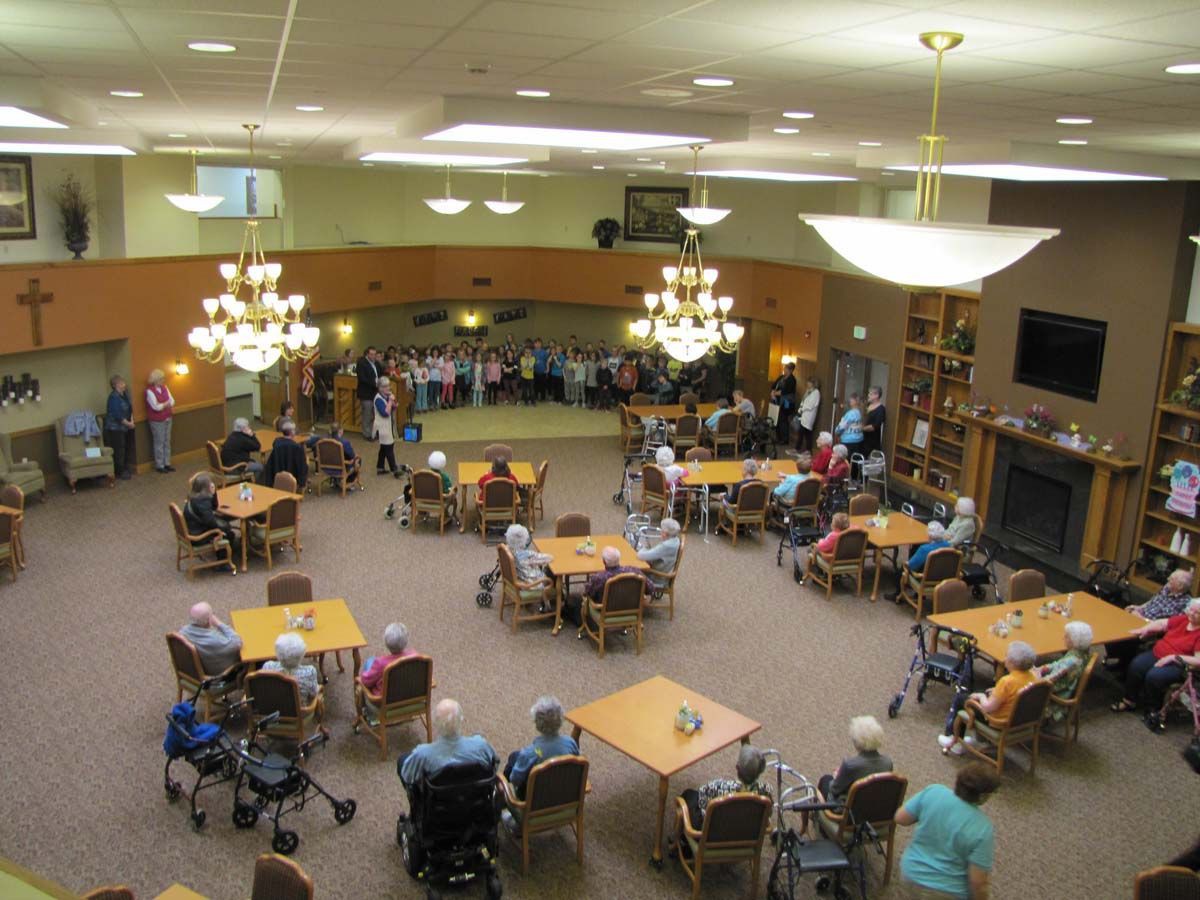A lively community hall filled with elderly people participating in activities, seated at tables.