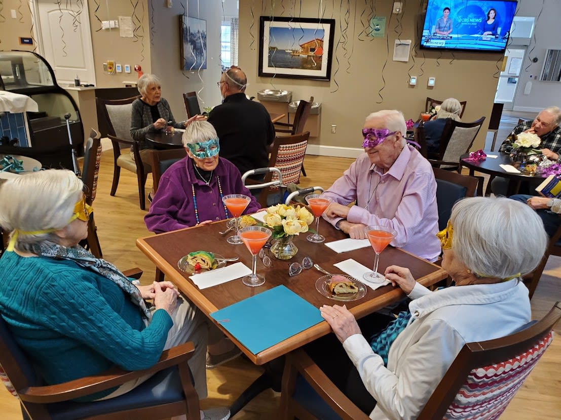 A group of seniors wearing masks and enjoying drinks together at a community gathering.