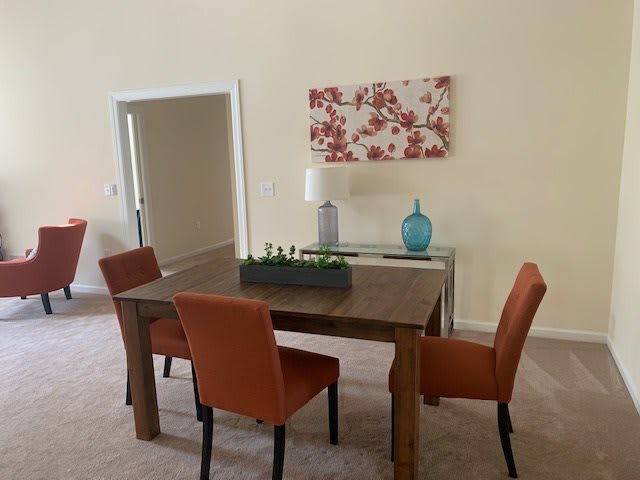 A cozy dining room with a wooden table, orange chairs, and decorative elements.