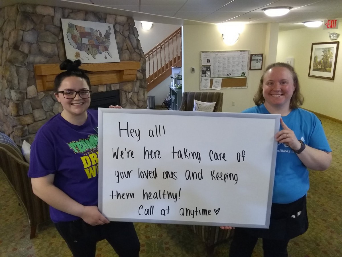 Two people holding a sign with a message offering care and support.