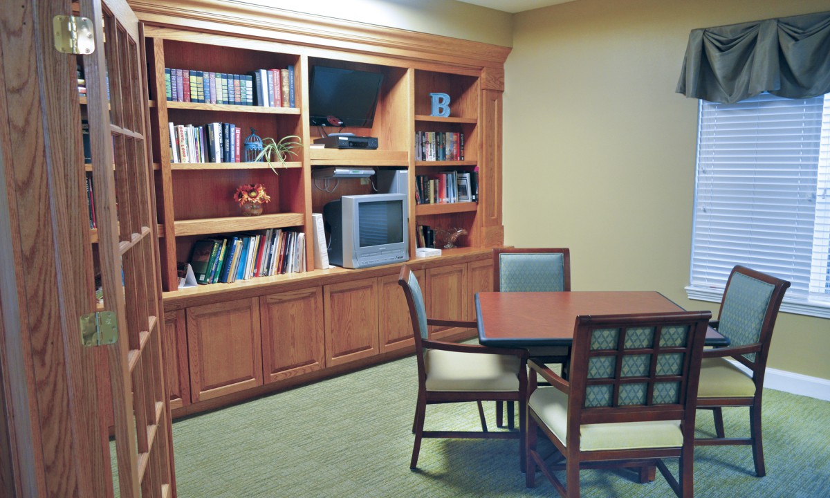 A cozy library corner with wooden bookshelves, a table, and chairs.