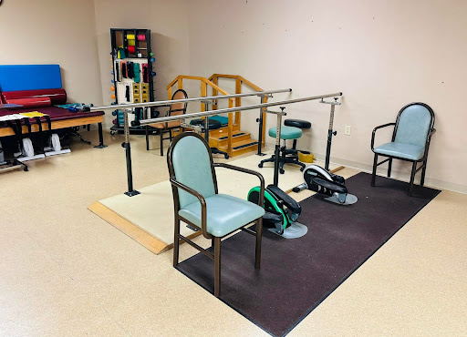 A rehabilitation therapy room equipped with exercise equipment and chairs for patient use.