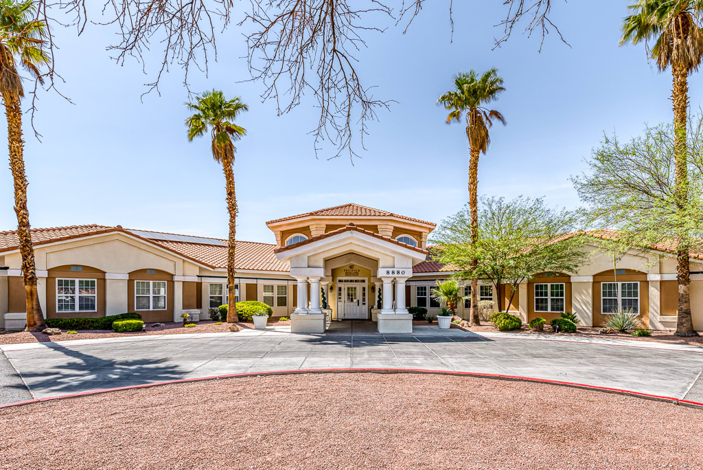 A luxurious house with palm trees and a circular driveway on a sunny day.