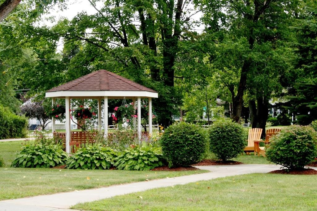 A peaceful park scene featuring a gazebo surrounded by lush greenery and a winding pathway.