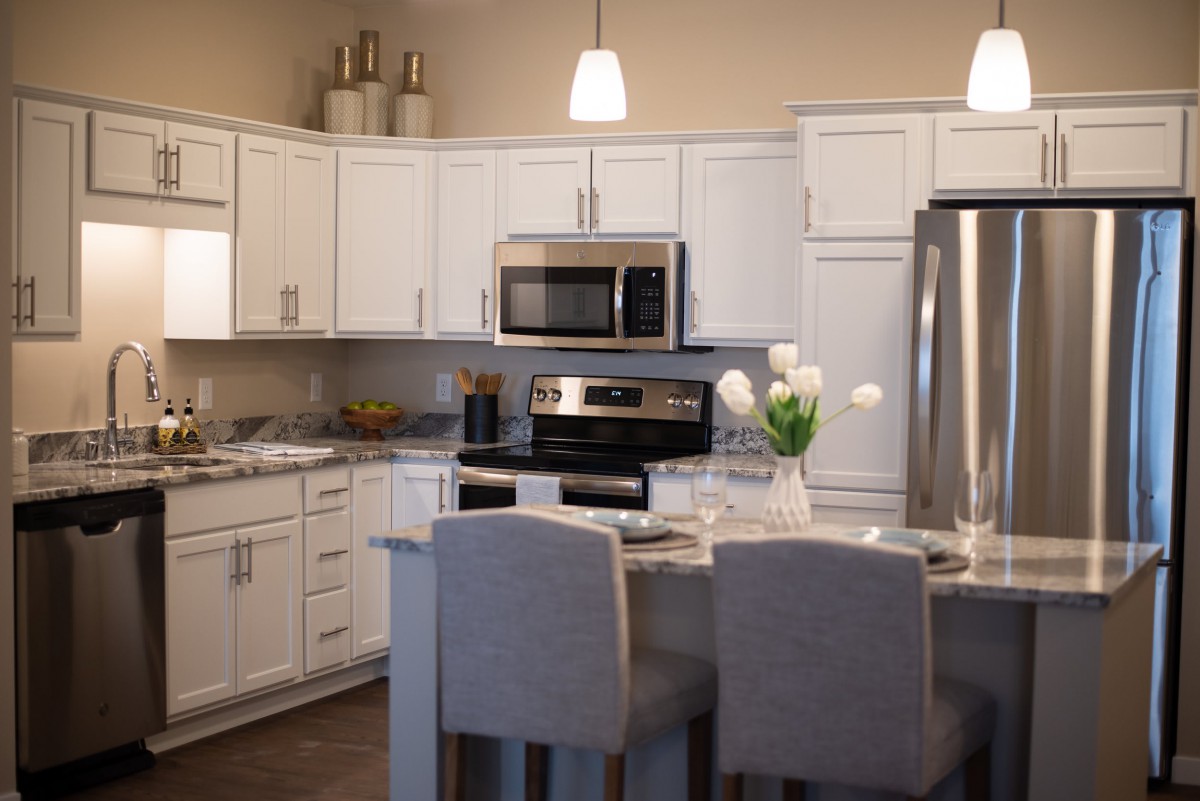 A modern kitchen with white cabinets, an island counter, and stainless steel appliances.