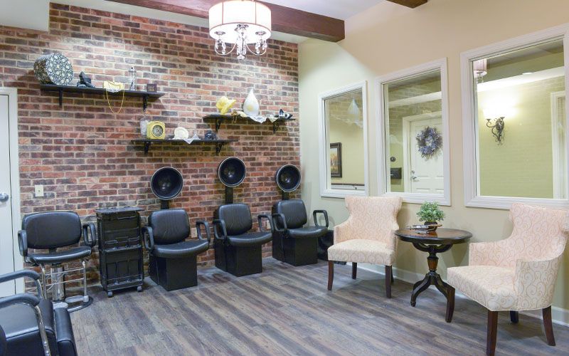 A modern salon interior featuring styling chairs and hair dryers against a brick wall, with an elegant waiting area.