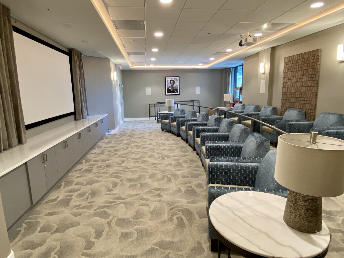 A modern conference room with organized seating and a projector screen, designed for meetings and presentations.