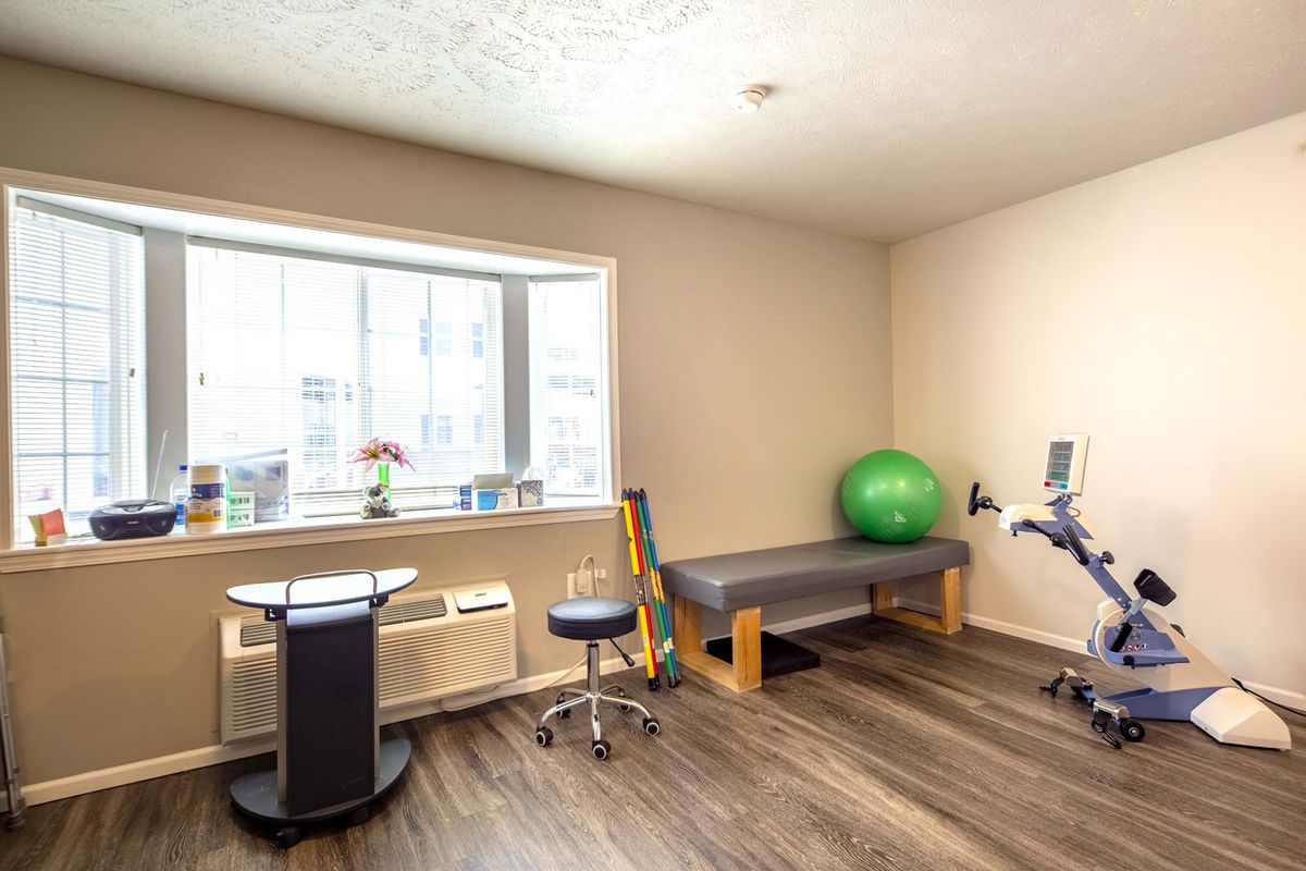 A well-lit physical therapy room equipped with an exercise ball, treatment table, and other rehabilitation tools.