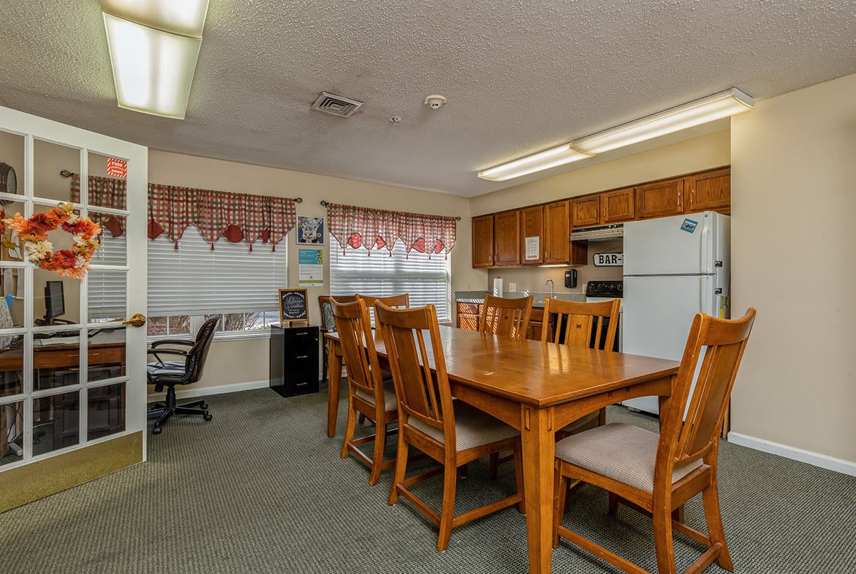 A combined kitchen and dining area with wooden furniture and an office corner.