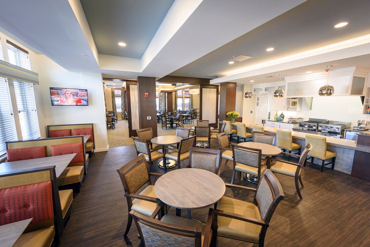 A modern dining area with multiple tables and chairs, featuring elegant lighting and decor.