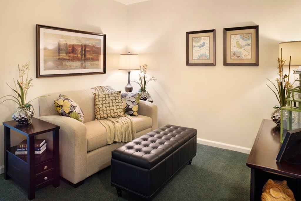 A cozy living room with a comfortable sofa, decorative pillows, a lamp, and framed artwork on the wall.