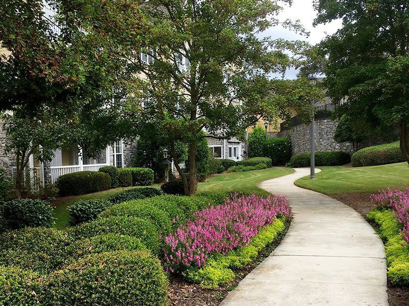 A beautifully landscaped garden path surrounded by trees and colorful plants.