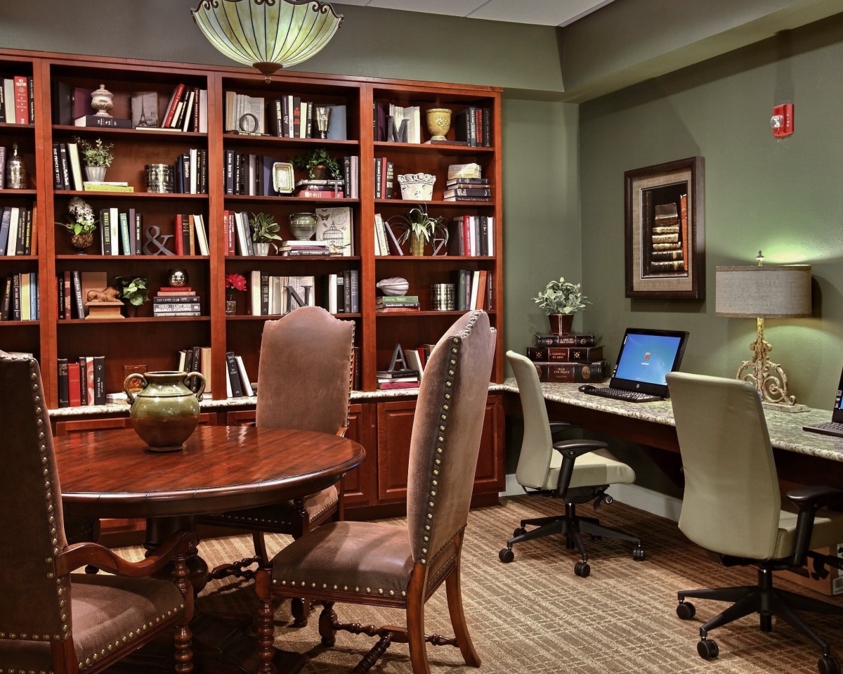 A well-organized office space with a large bookshelf, comfortable seating, and a computer workstation.