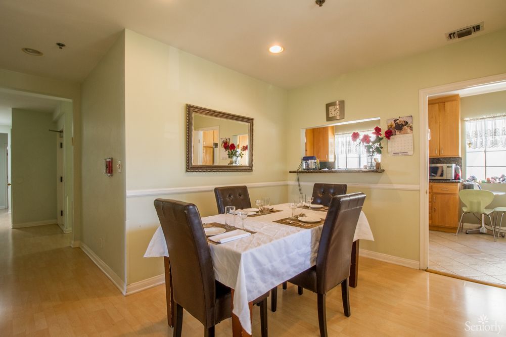 A cozy dining area featuring a neatly set table with chairs and a mirror on the wall.