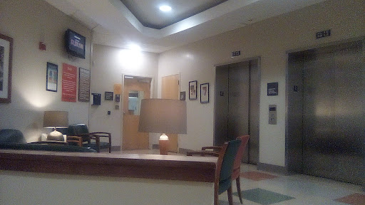 A quiet hospital lobby featuring a cozy waiting area with an elevator in the background.