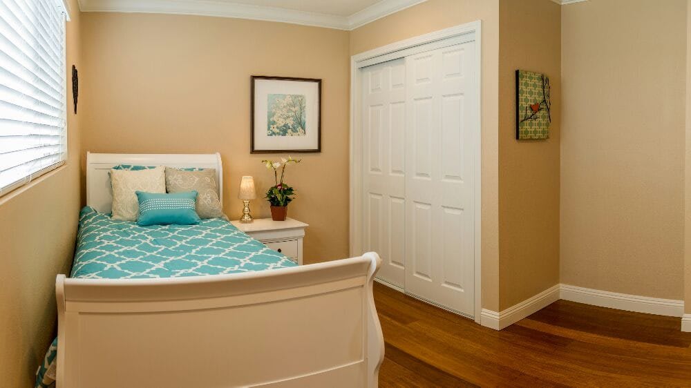 A cozy bedroom with a bed, nightstand, lamp, and closet.