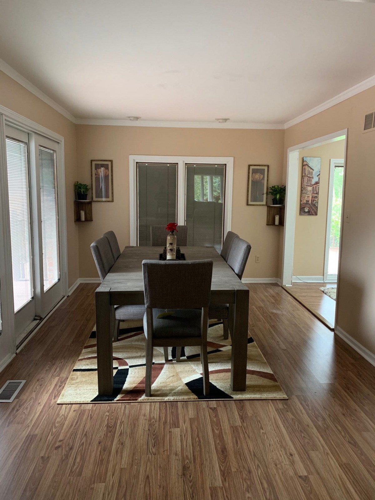 A neatly arranged dining room with a table set, surrounded by chairs and decorated with wall art.