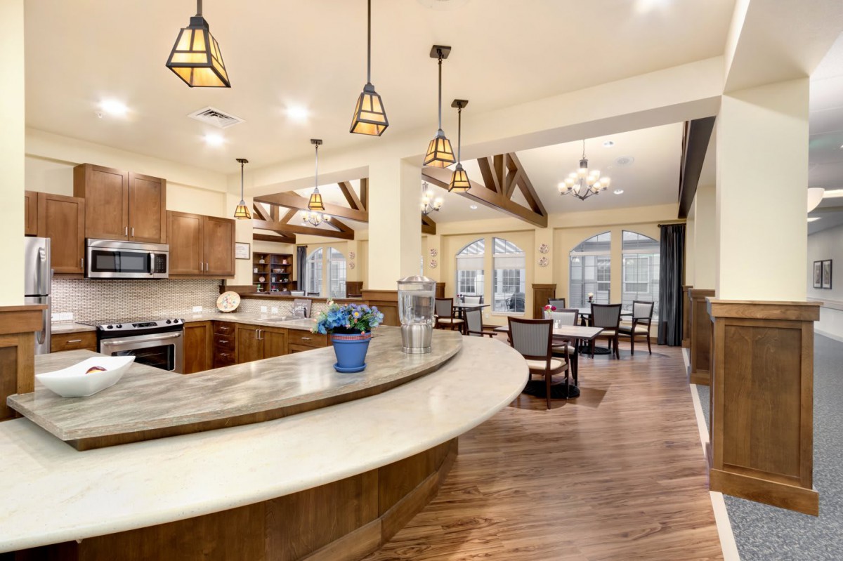 A spacious open-concept kitchen and dining area featuring modern design with wood flooring, pendant lighting, and granite countertops.
