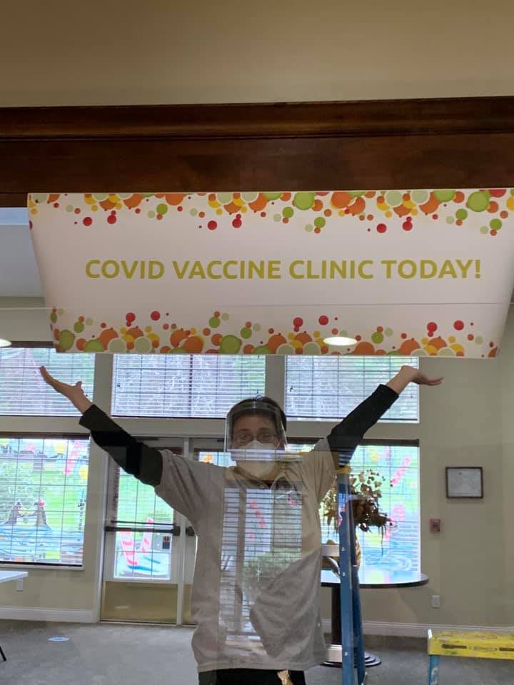 Healthcare worker at a COVID vaccine clinic with arms raised in celebration.