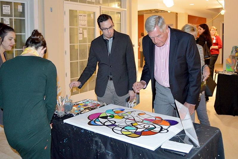 People engaged with a colorful painting at an indoor event.