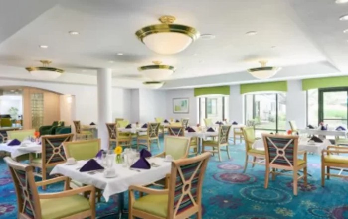 An elegant dining area with well-set tables, featuring natural lighting and stylish decor.