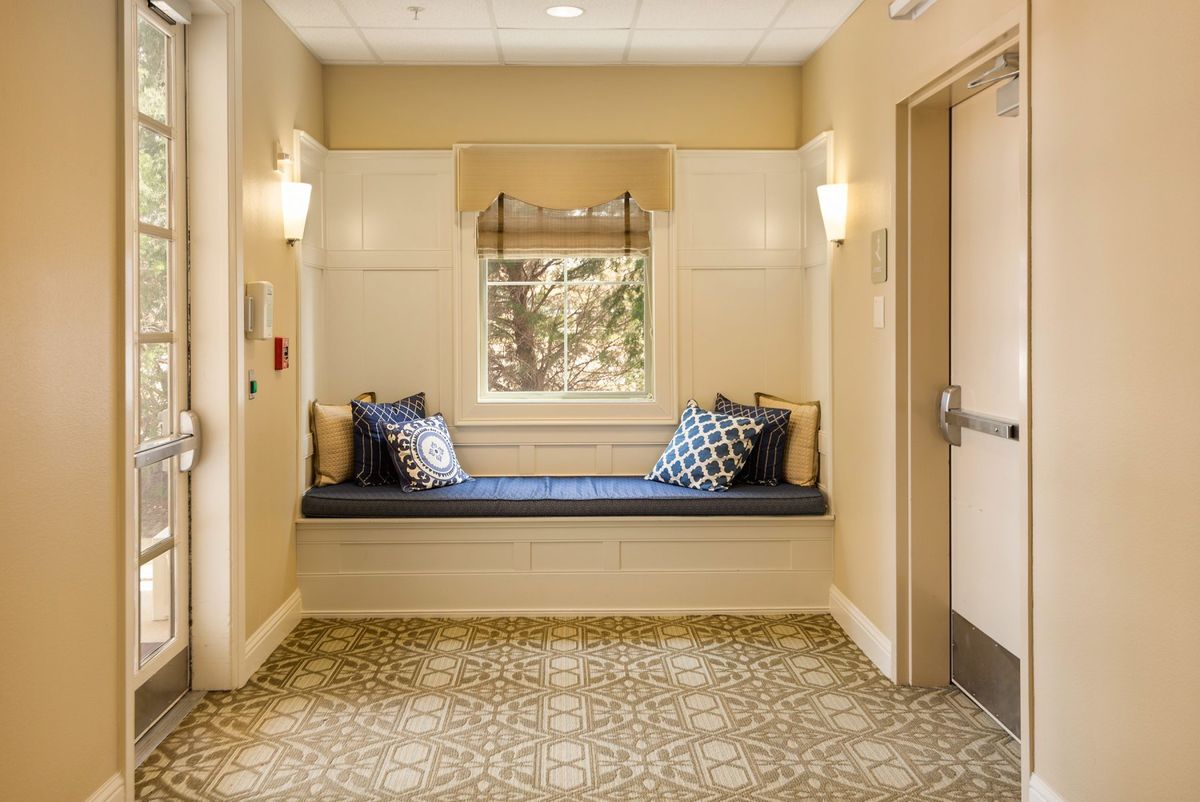 A cozy window seat in a well-lit hallway with elegant decor.