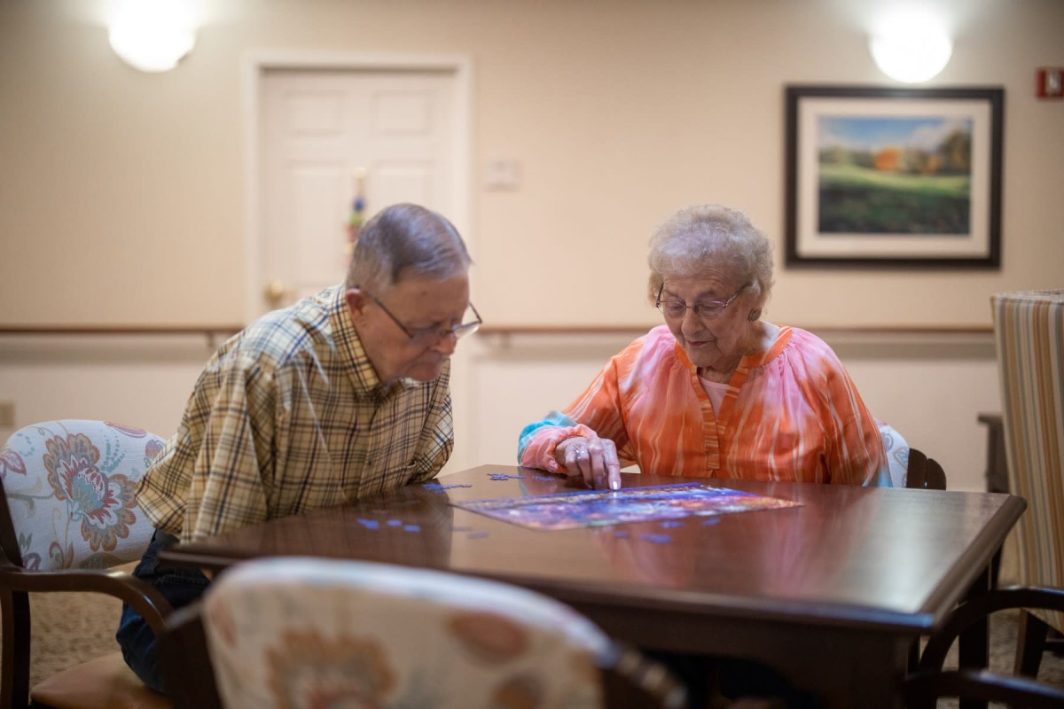 An elderly couple working on a puzzle together at a table.