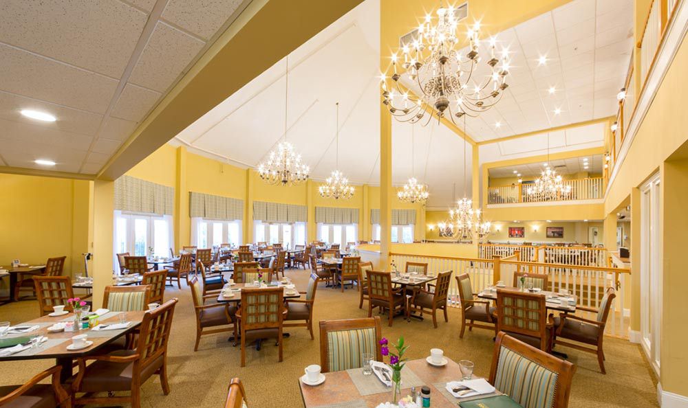 A spacious and elegantly decorated dining room with chandeliers, set with tables and chairs.