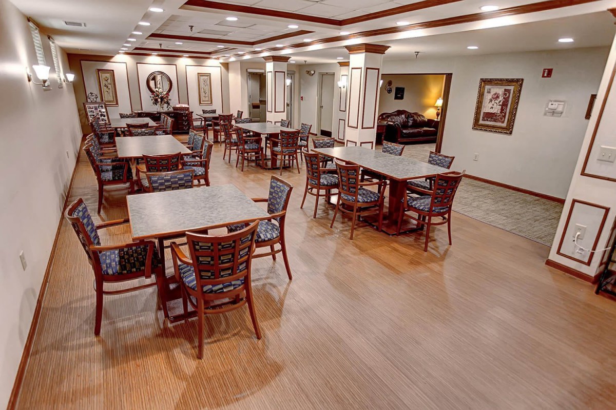 A spacious dining area with neatly arranged tables and chairs, featuring wood flooring and decorative elements.