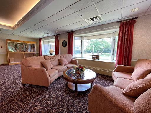 A cozy living room setting featuring comfortable sofas and a coffee table, with natural light streaming in through large windows.