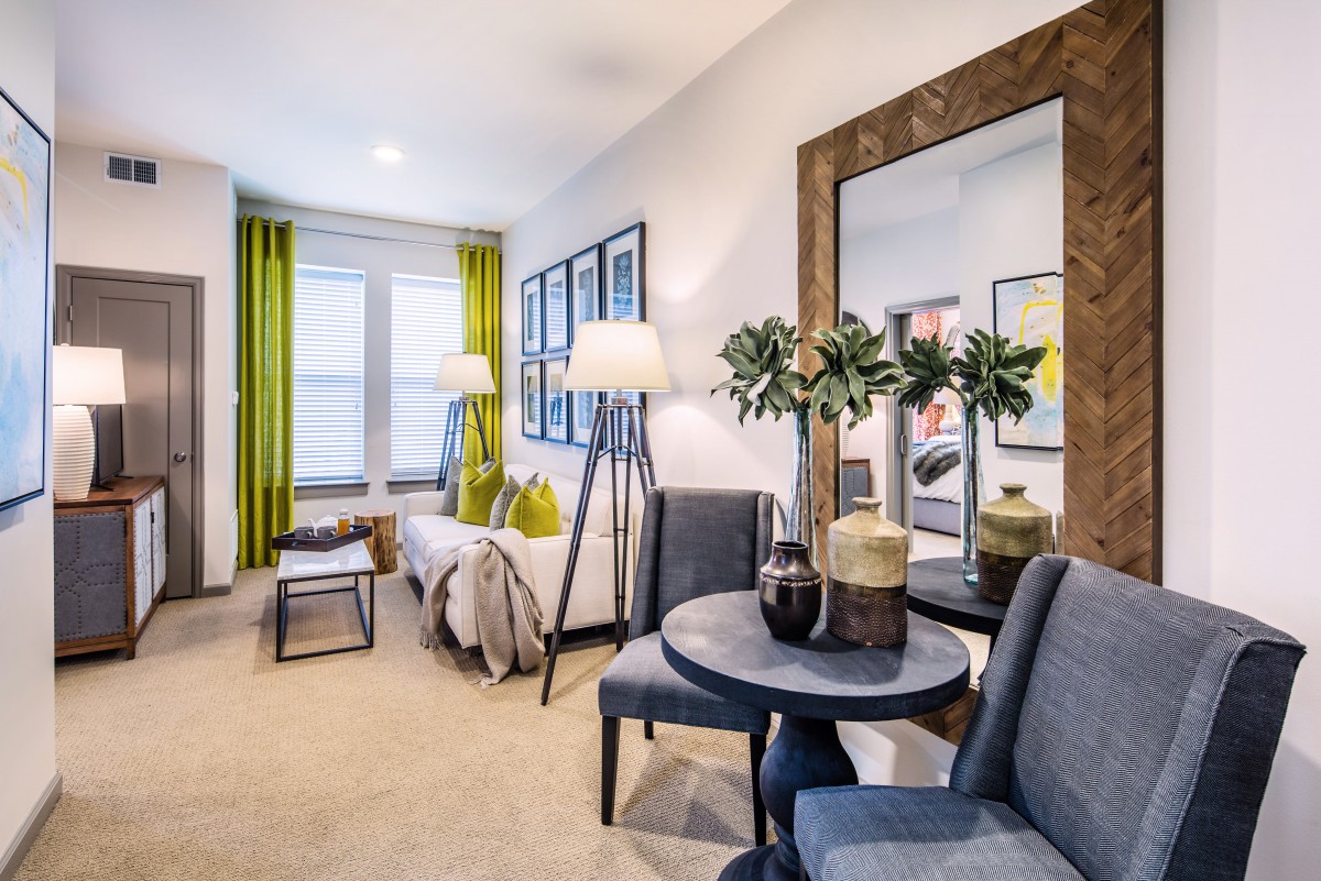 A modern living room with vibrant green curtains, stylish furniture, and a large mirror adding depth to the space.