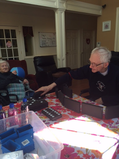 Two elderly individuals engaged in a playful activity at a table, showcasing their enjoyable interaction.