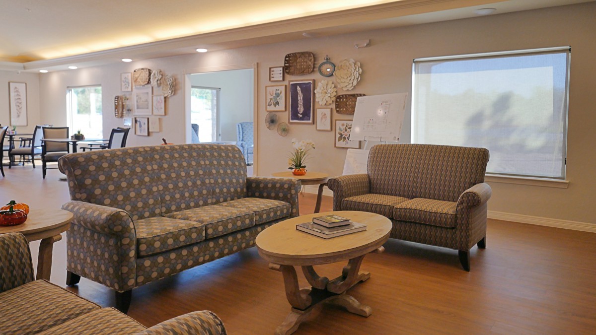 A cozy living room with patterned sofas and a wooden coffee table, decorated with wall art.