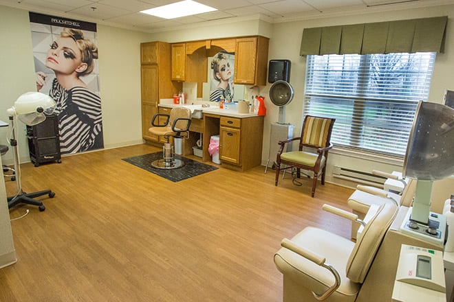 A cozy salon interior with styling chairs and mirrors, featuring wall posters and wooden flooring.