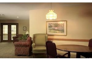 A cozy living room with a sofa, chairs, and a small table under a decorative lamp.