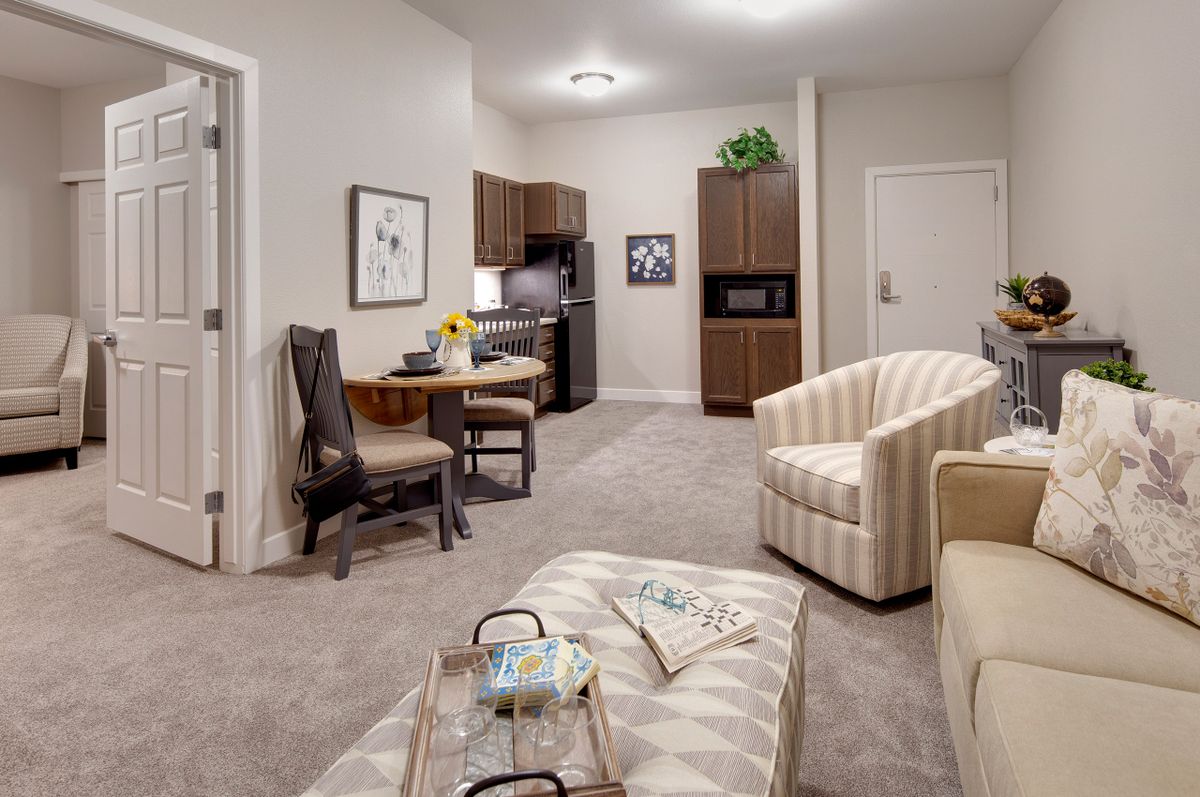 A cozy and modern apartment living area featuring comfortable furniture and a kitchenette.