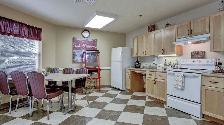 A break room kitchen with dining area, featuring a refrigerator, microwave, and ample seating.