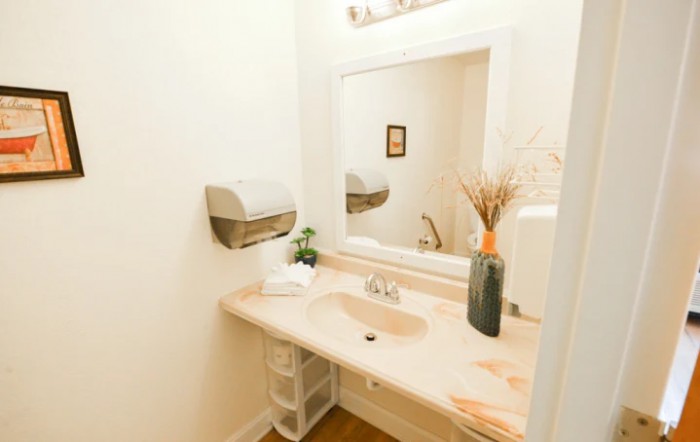 A clean bathroom with a large mirror, sink, and decorative elements.