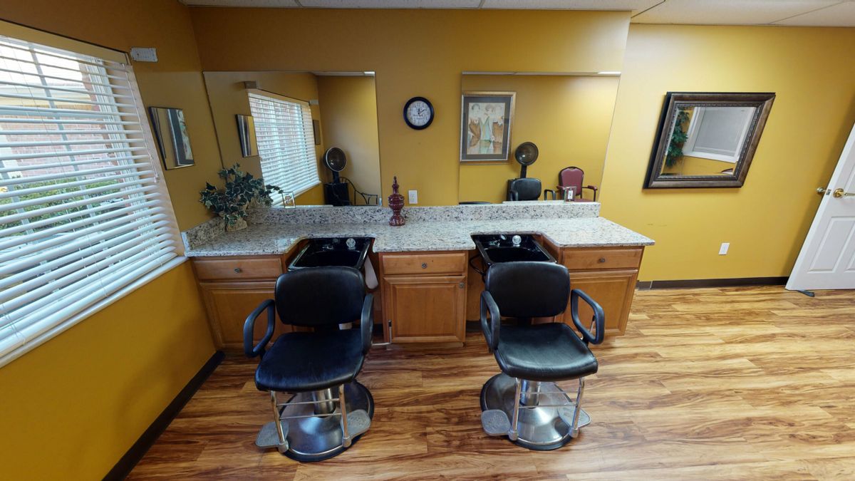 A cozy hair salon with two barber chairs and mirrors.