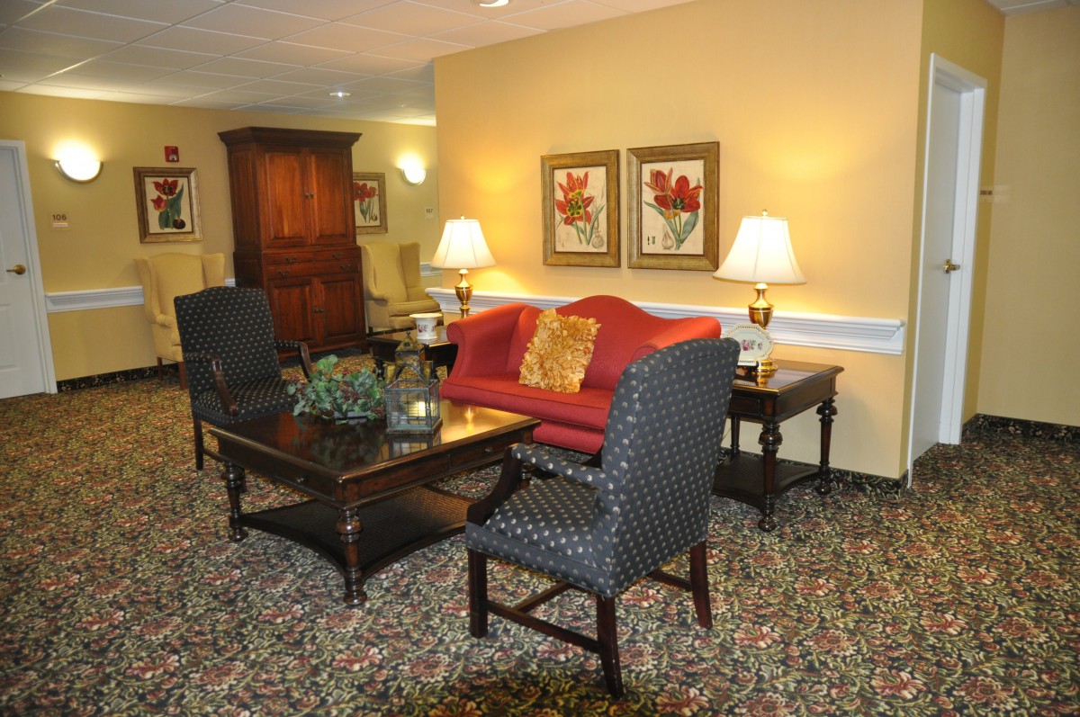 A cozy living room with a red sofa, patterned chairs, and warm lighting.