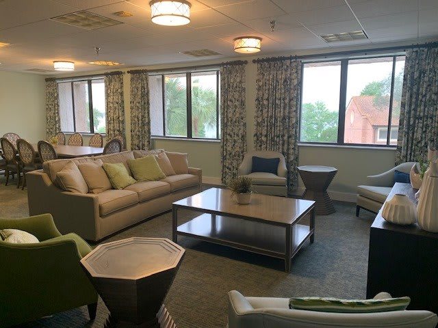 A cozy living room featuring comfortable sofas, a coffee table, and large windows with curtains.