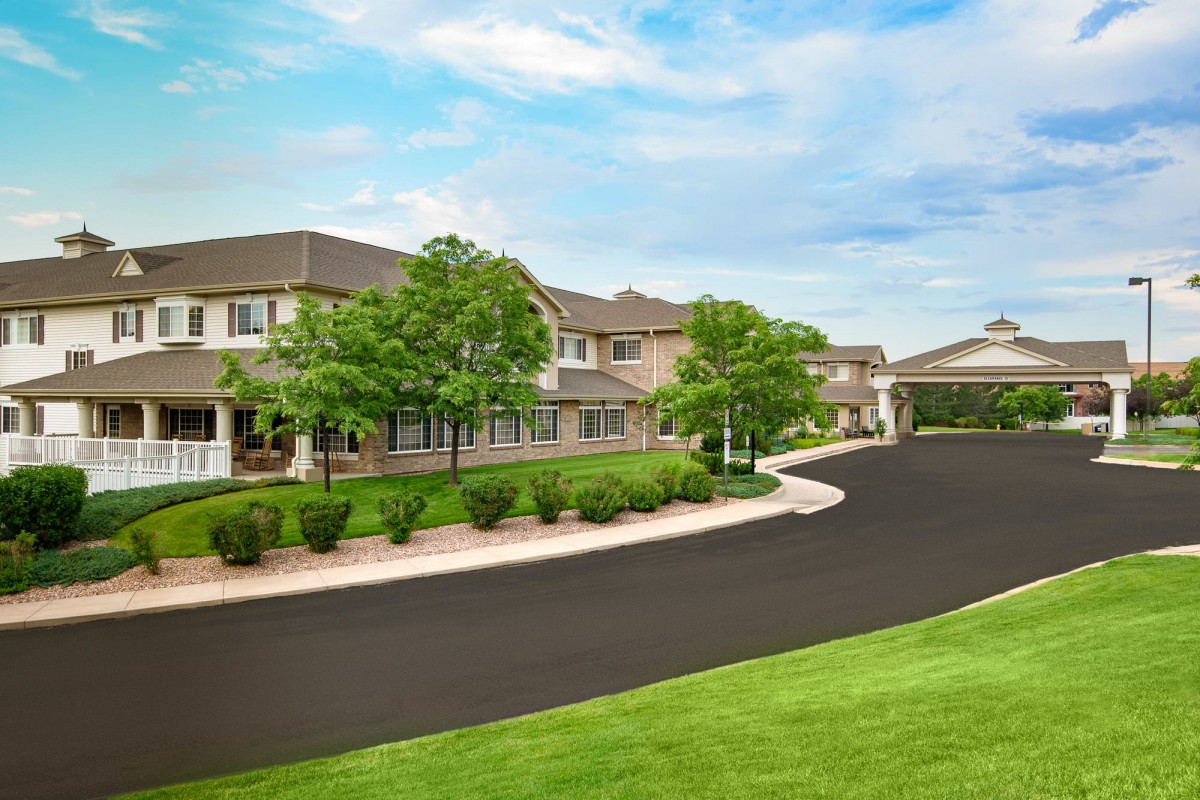 A scenic view of a residential building with a lush green landscape and clear blue sky.
