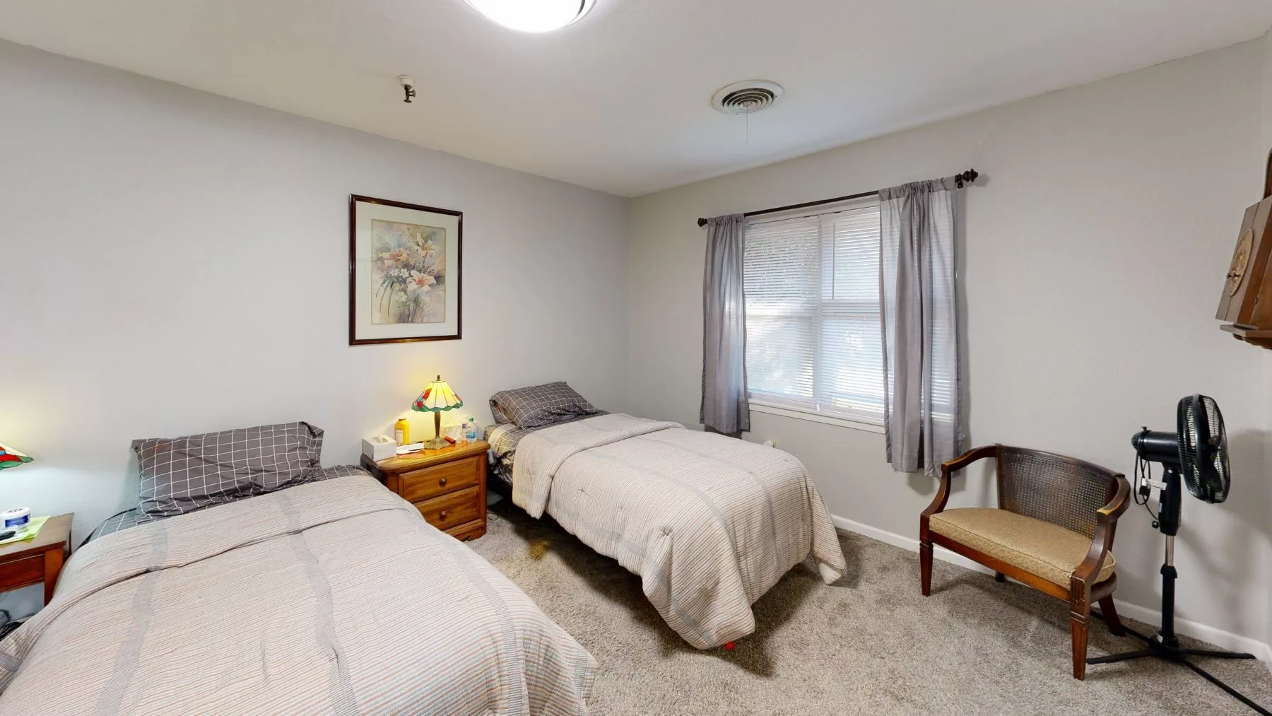 A cozy bedroom featuring two twin beds with a window and nightstand between them.
