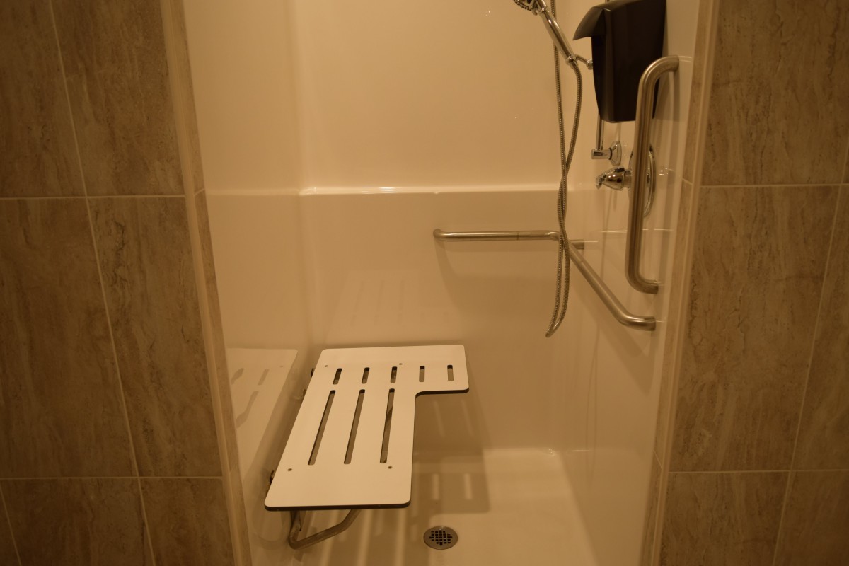 An accessible shower stall featuring a shower bench and handrails for safety.