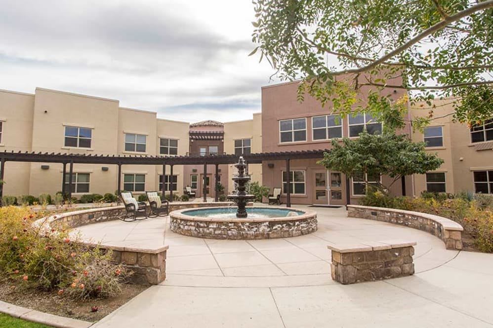 A modern courtyard featuring a central fountain surrounded by a building with outdoor seating areas.