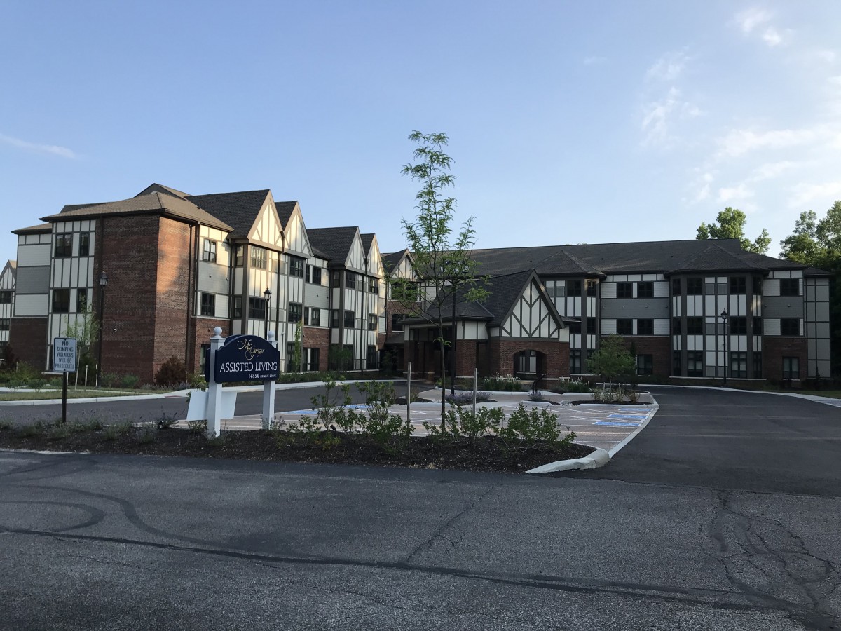 A residential building with Tudor-style architecture surrounded by a paved road and greenery at sunset.