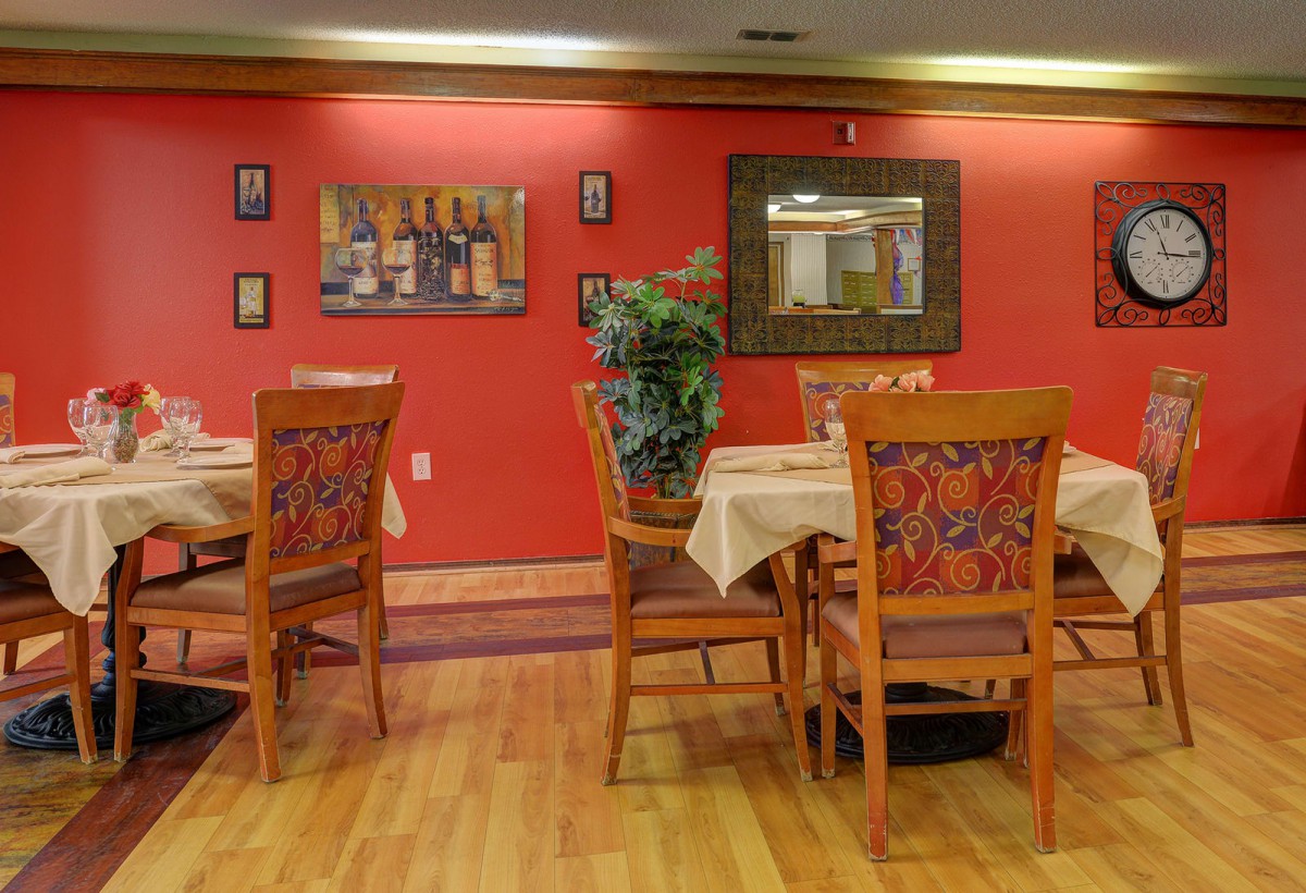 A cozy restaurant dining area with wooden tables and chairs, adorned with wall art.