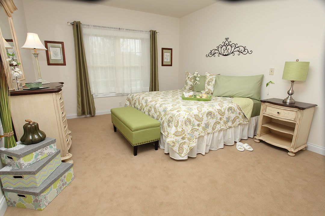 A cozy bedroom with a floral bedspread and matching ottoman.