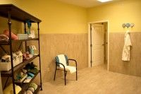 A small, cozy waiting room with a chair and shelves stocked with towels.